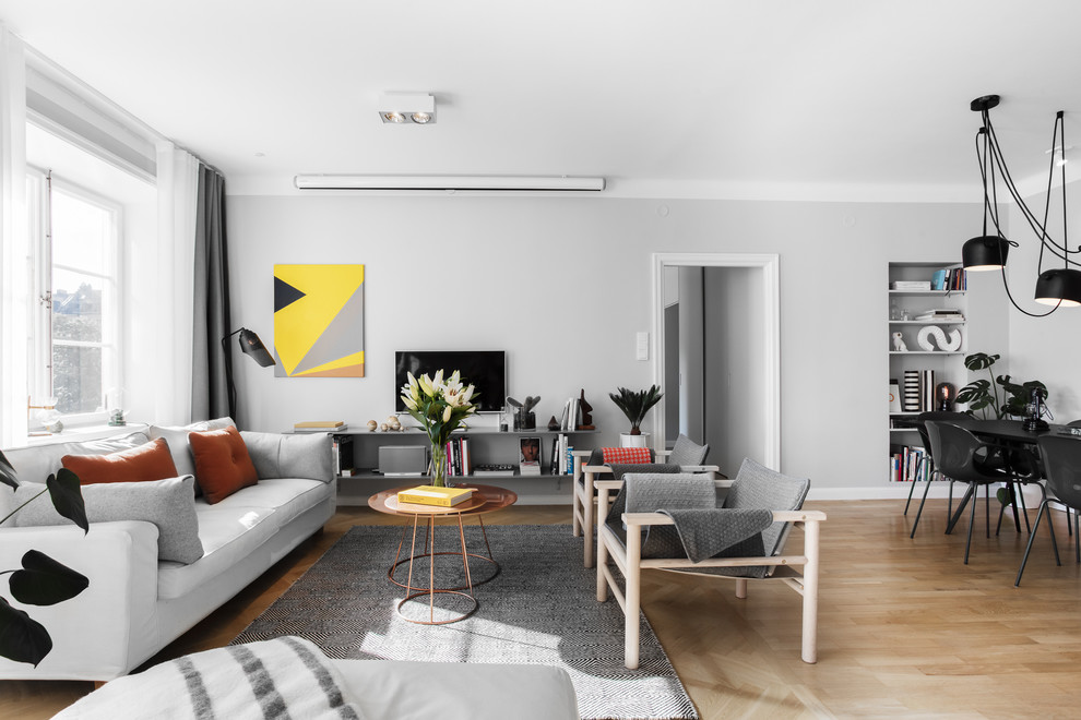 Photo of a medium sized scandi living room in Stockholm with white walls, medium hardwood flooring, a freestanding tv and beige floors.
