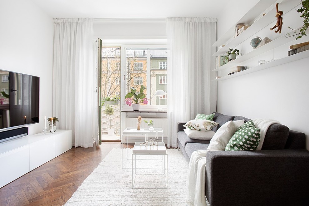 Esempio di un soggiorno scandinavo chiuso con pareti bianche, pavimento in legno massello medio, nessun camino, TV a parete e pavimento marrone