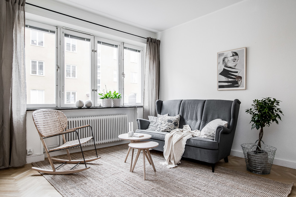 Photo of a scandi living room in Stockholm with white walls, light hardwood flooring and beige floors.
