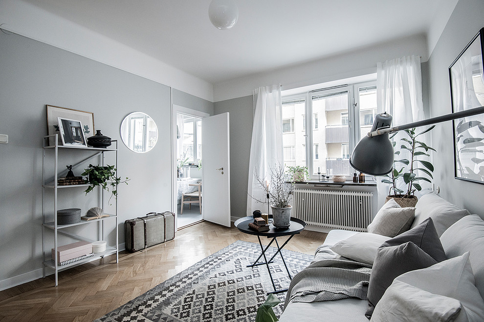 This is an example of a small scandi enclosed living room in Stockholm with grey walls, medium hardwood flooring and brown floors.