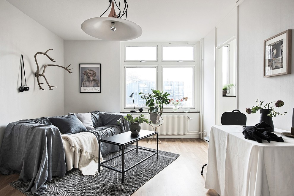 Foto på ett mellanstort skandinaviskt vardagsrum, med vita väggar och ljust trägolv
