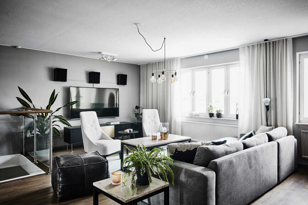 Источник вдохновения для домашнего уюта: большая парадная, изолированная гостиная комната в современном стиле с серыми стенами, паркетным полом среднего тона, телевизором на стене и коричневым полом без камина