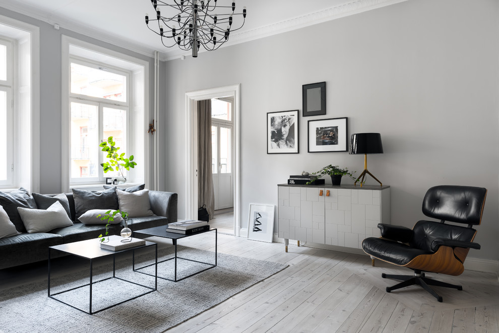 На фото: гостиная комната в скандинавском стиле с серыми стенами, светлым паркетным полом и бежевым полом с