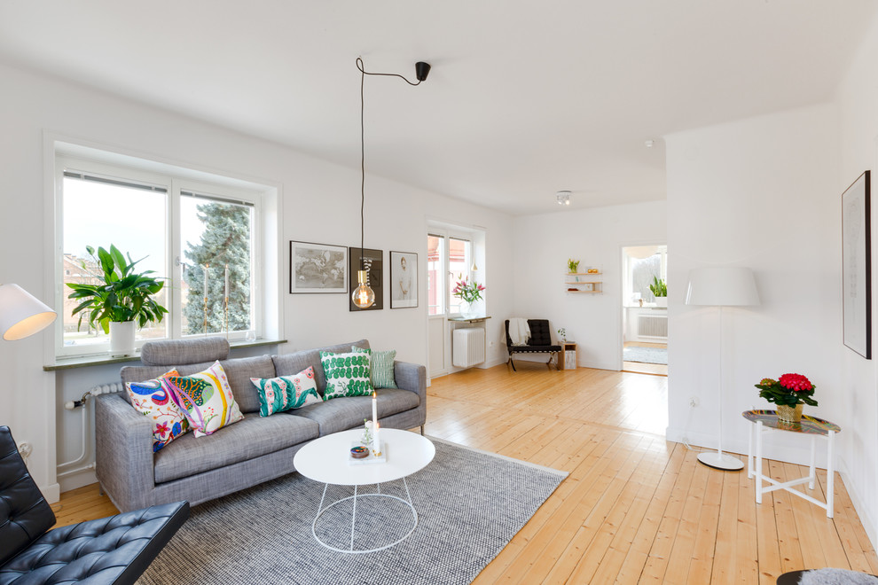 Idee per un grande soggiorno scandinavo aperto con pareti bianche, pavimento in legno massello medio, nessun camino e nessuna TV