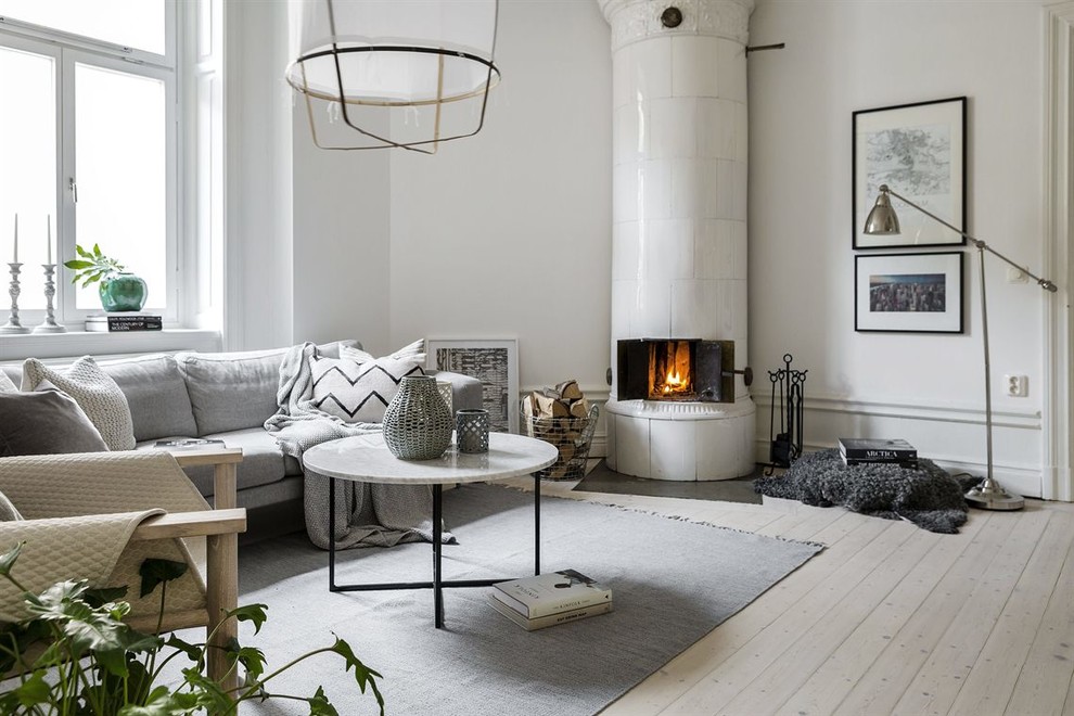 Idee per un soggiorno scandinavo di medie dimensioni e aperto con pareti bianche, parquet chiaro, stufa a legna, cornice del camino piastrellata, nessuna TV e sala formale