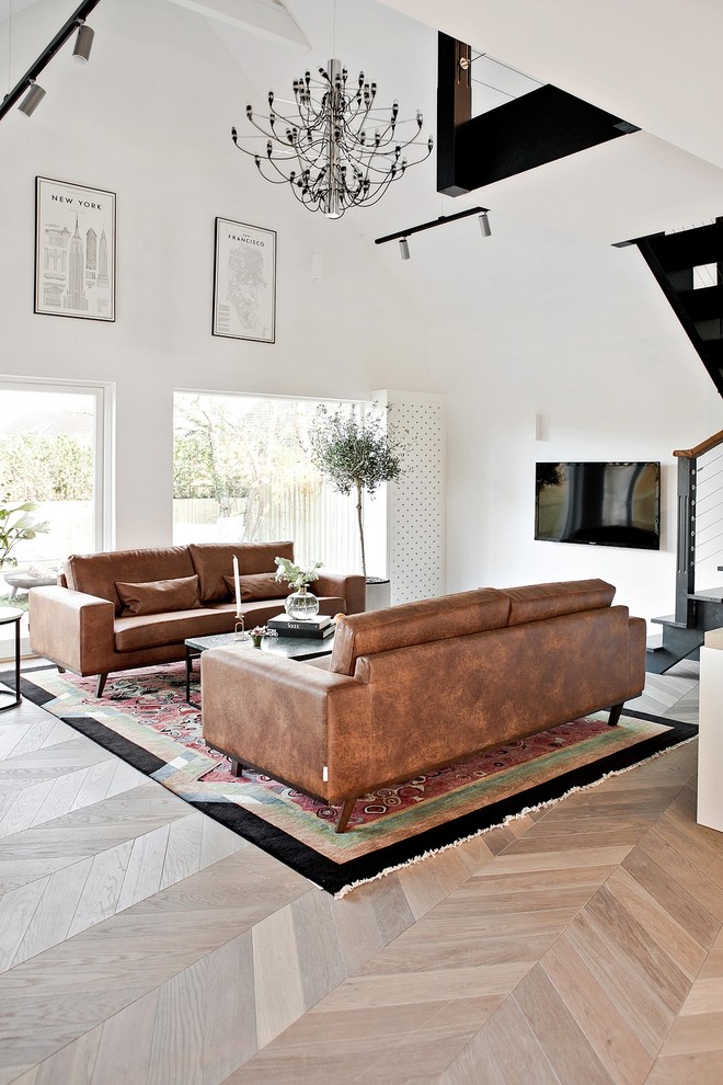 Großes, Offenes Modernes Wohnzimmer mit weißer Wandfarbe, hellem Holzboden, beigem Boden und TV-Wand in Malmö