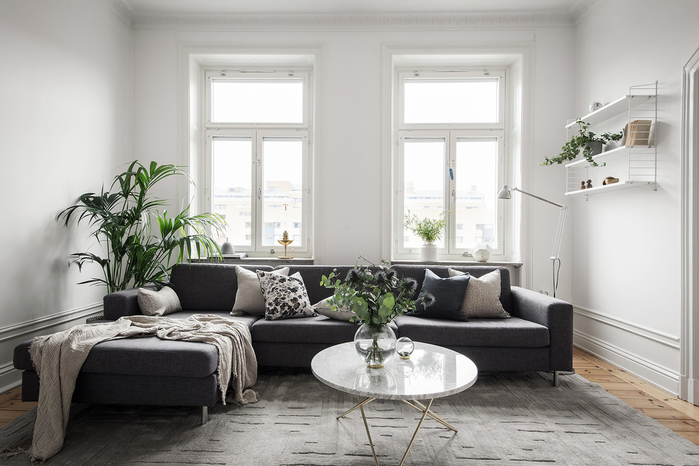 Nordisches Wohnzimmer mit weißer Wandfarbe, braunem Holzboden und braunem Boden in Stockholm