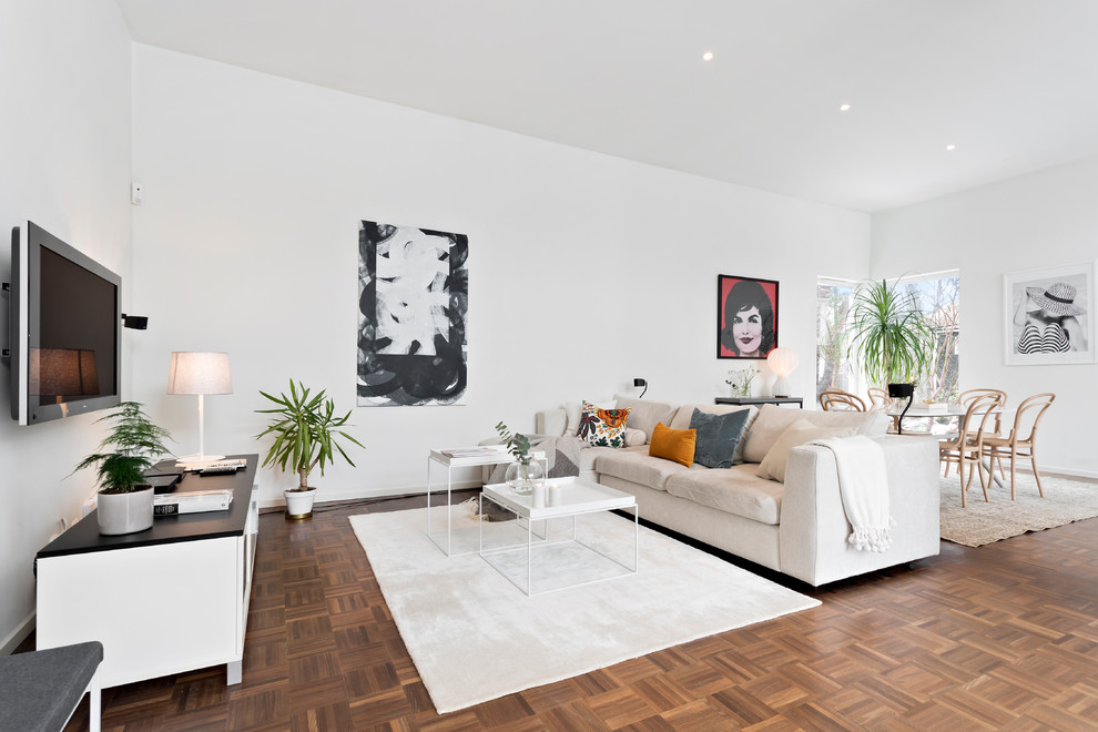 Bild på ett mellanstort minimalistiskt allrum med öppen planlösning, med vita väggar, en väggmonterad TV, brunt golv och mellanmörkt trägolv