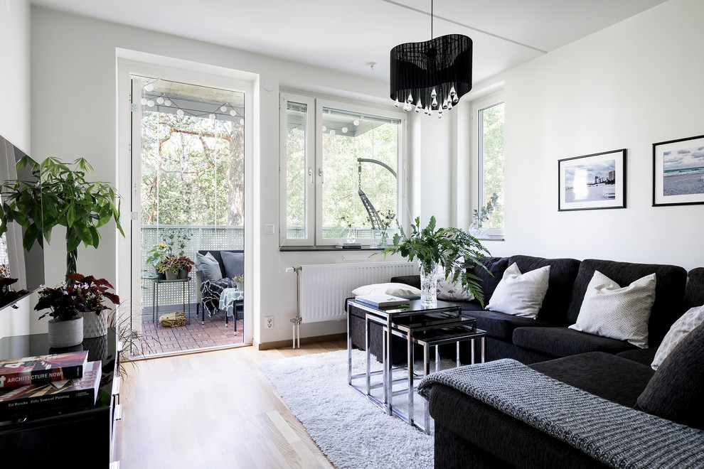 Photo of a medium sized scandi enclosed living room in Stockholm with white walls, light hardwood flooring, beige floors and a wall mounted tv.