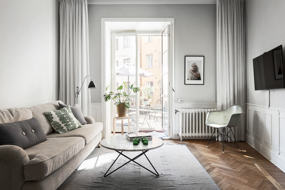 Стильный дизайн: открытая, парадная гостиная комната среднего размера в скандинавском стиле с серыми стенами, темным паркетным полом и телевизором на стене - последний тренд