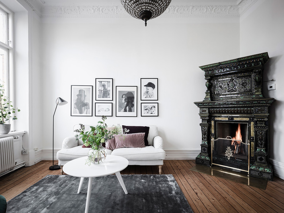 Repräsentatives, Abgetrenntes Nordisches Wohnzimmer mit weißer Wandfarbe, dunklem Holzboden, Eckkamin, gefliester Kaminumrandung und braunem Boden in Göteborg