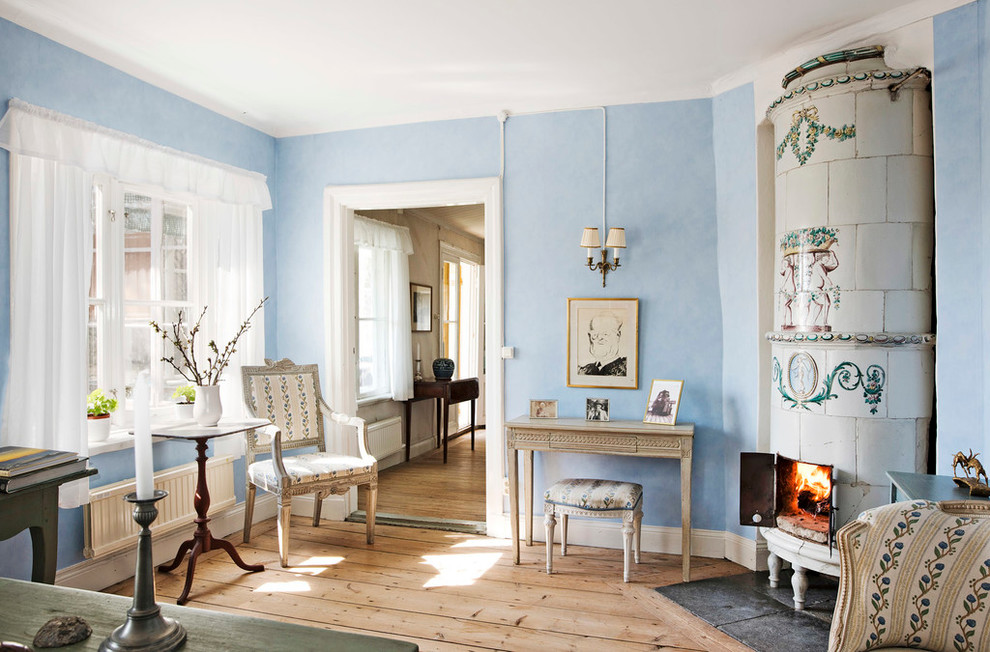 Inredning av ett lantligt mellanstort separat vardagsrum, med blå väggar, ljust trägolv, en öppen hörnspis och ett finrum