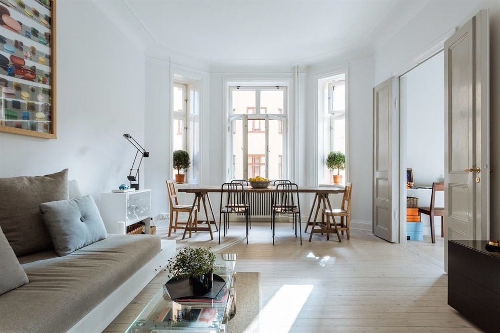 На фото: парадная, открытая гостиная комната в скандинавском стиле с белыми стенами и светлым паркетным полом без камина, телевизора