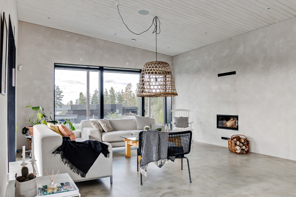На фото: открытая, парадная гостиная комната среднего размера в скандинавском стиле с серыми стенами, бетонным полом, горизонтальным камином и серым полом без телевизора с