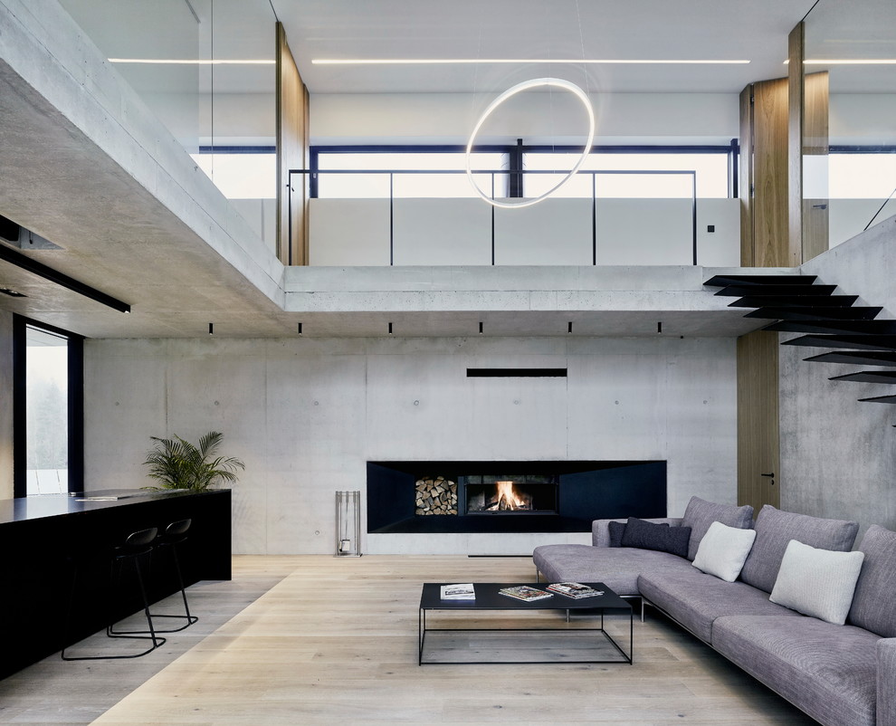 Immagine di un soggiorno moderno con pareti grigie, parquet chiaro, camino classico e pavimento beige