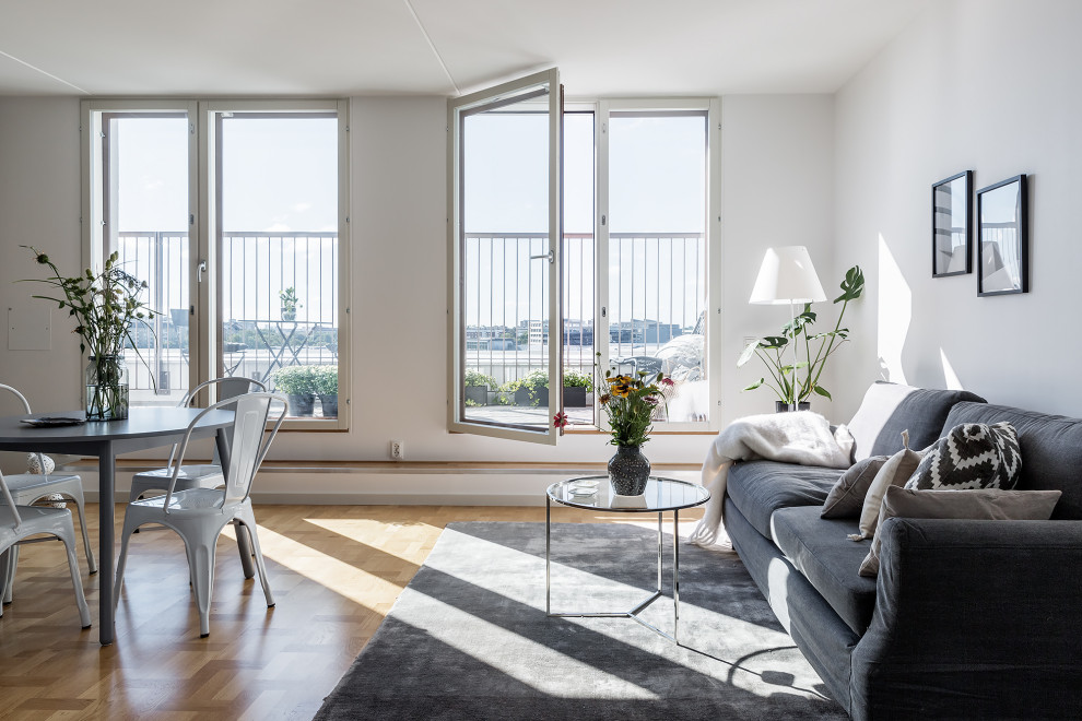 Living room - scandinavian open concept medium tone wood floor and brown floor living room idea in Stockholm with white walls