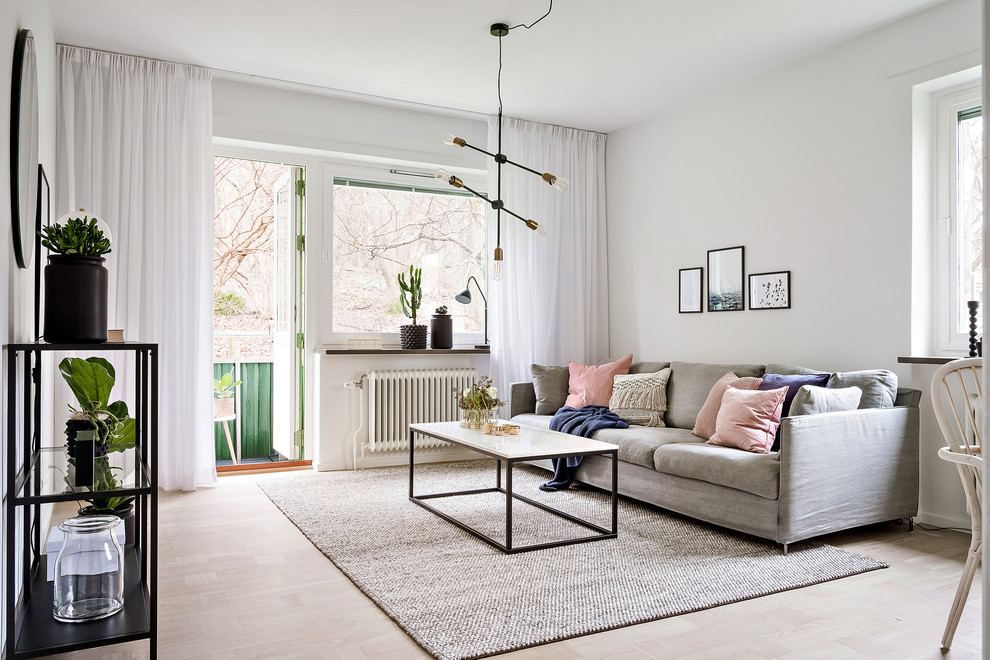 Bild på ett minimalistiskt vardagsrum, med vita väggar, ljust trägolv och beiget golv