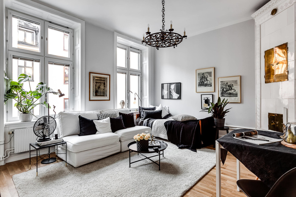 Kleines, Offenes Nordisches Wohnzimmer mit weißer Wandfarbe, braunem Holzboden, Eckkamin, gefliester Kaminumrandung und braunem Boden in Stockholm