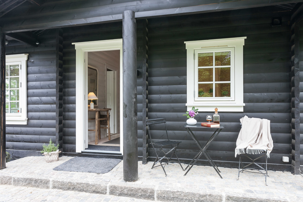 Inredning av en skandinavisk mellanstor veranda framför huset, med naturstensplattor