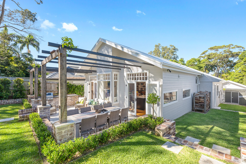 Klassische Veranda hinter dem Haus mit Outdoor-Küche, Natursteinplatten und Pergola in Sydney