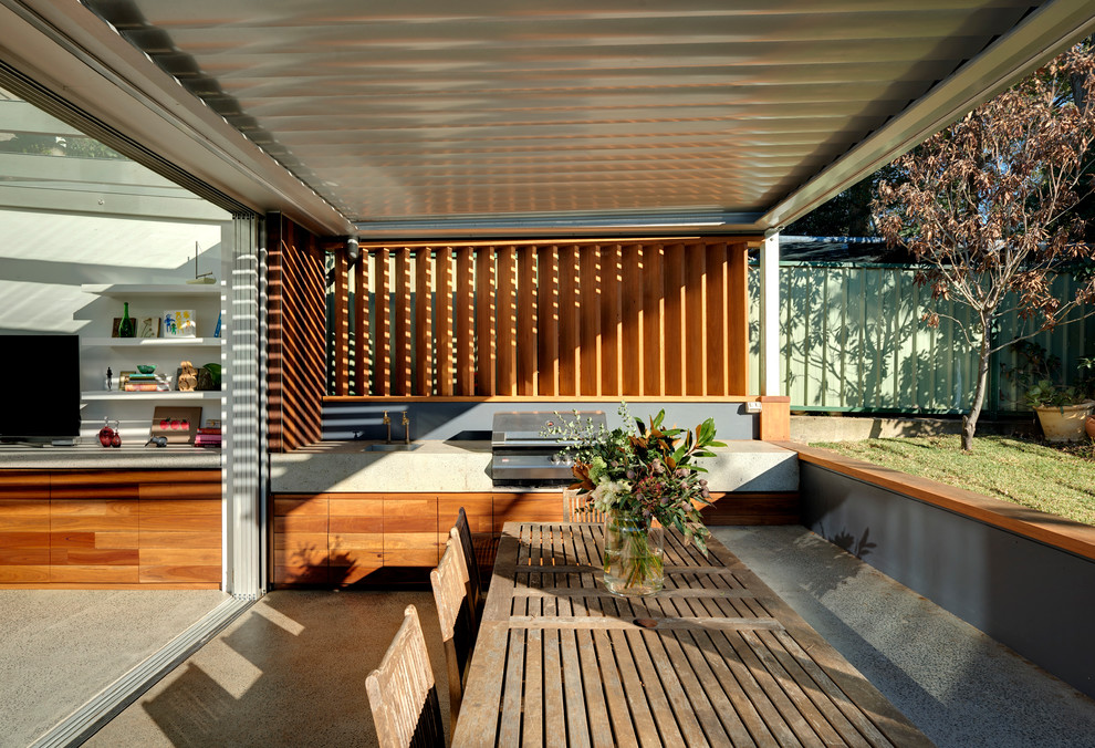 Idée de décoration pour un grand porche d'entrée de maison arrière design avec une dalle de béton et une extension de toiture.