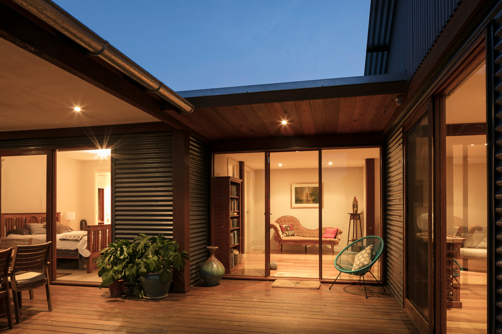 Aménagement d'un porche d'entrée de maison avant éclectique de taille moyenne avec une terrasse en bois et une extension de toiture.