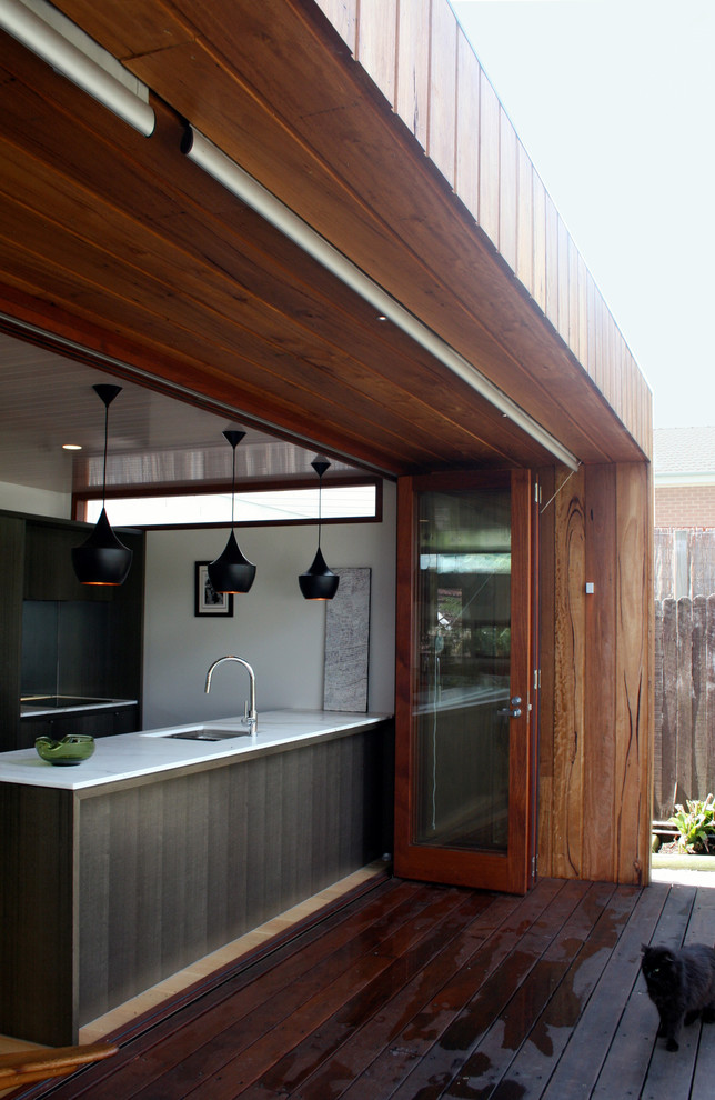 Exemple d'un petit porche d'entrée de maison arrière moderne avec une cuisine d'été, une terrasse en bois et une extension de toiture.