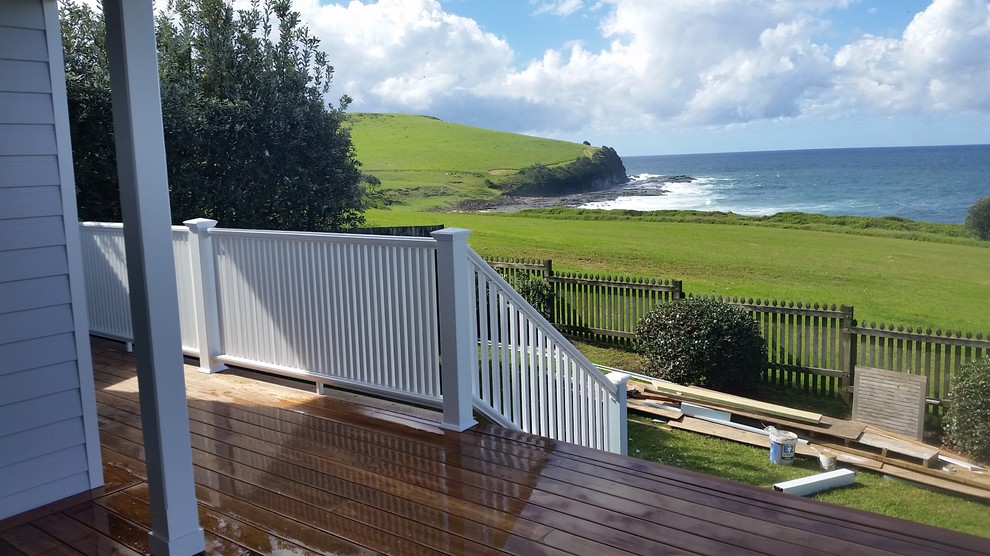 Mid-sized farmhouse screened-in front porch idea in Wollongong with decking