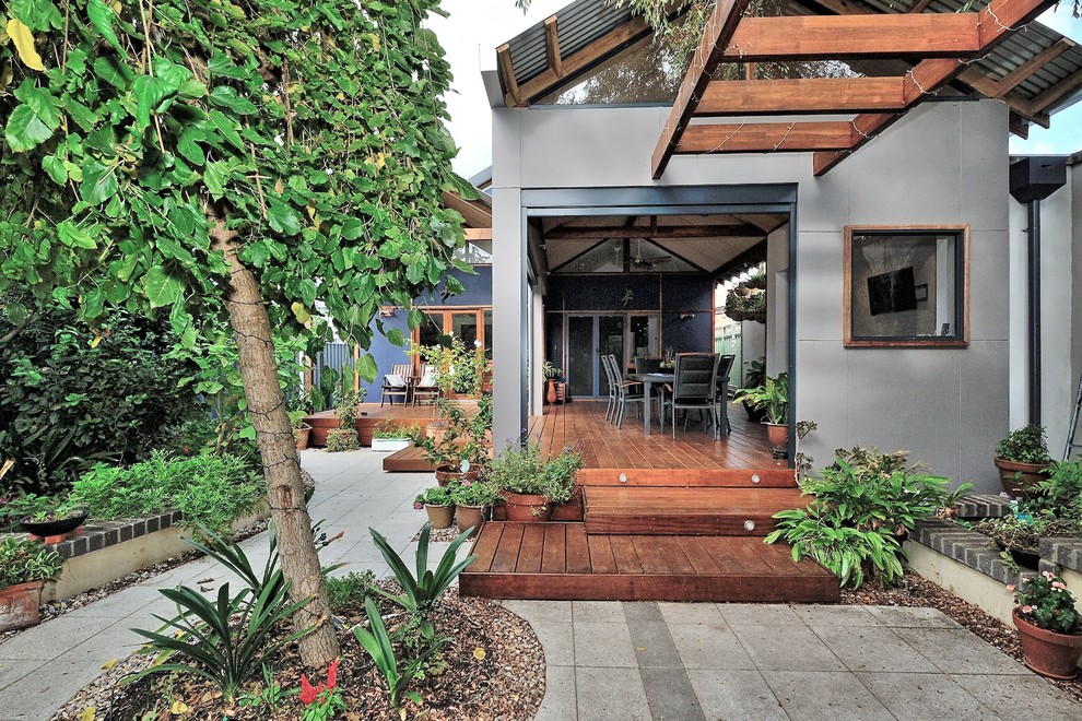 Réalisation d'un grand porche d'entrée de maison arrière avec une moustiquaire, une terrasse en bois et une extension de toiture.