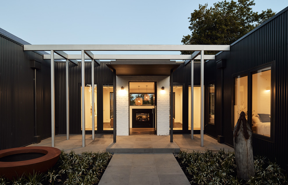Inspiration pour un grand porche d'entrée de maison avant design avec une cheminée, des pavés en pierre naturelle et une pergola.