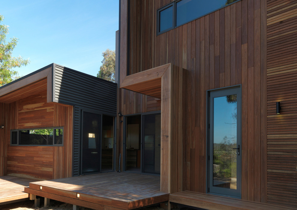 Idée de décoration pour un porche d'entrée de maison arrière design avec une terrasse en bois et une extension de toiture.