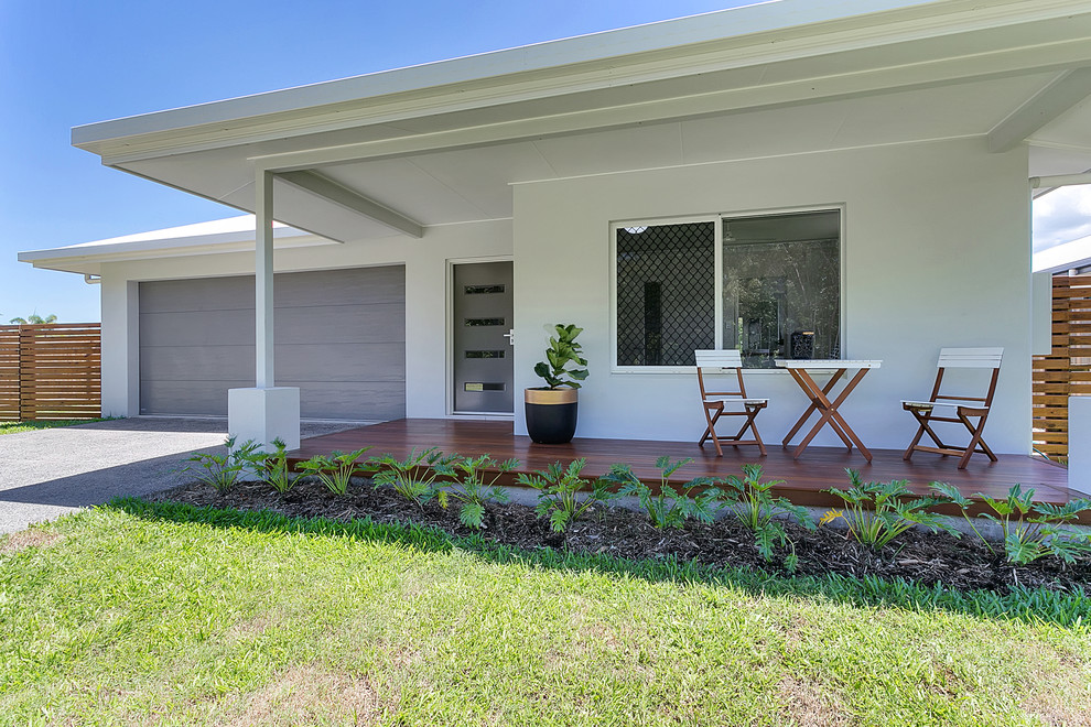 Aménagement d'un porche d'entrée de maison avant exotique de taille moyenne avec une terrasse en bois et une extension de toiture.
