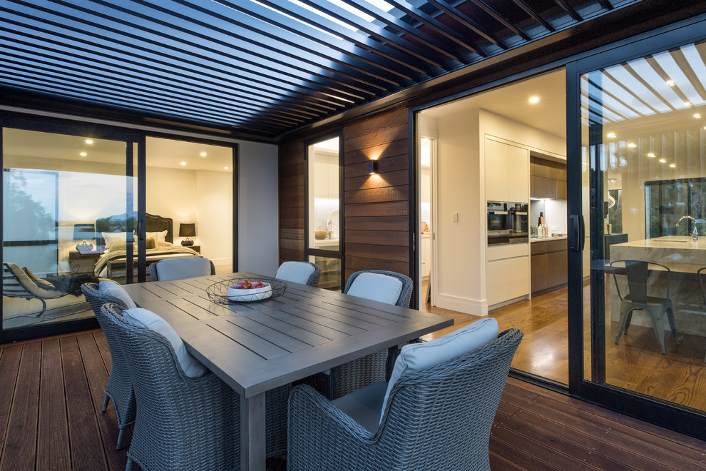 This is an example of a mid-sized contemporary screened-in side porch design in Auckland with decking and a pergola.