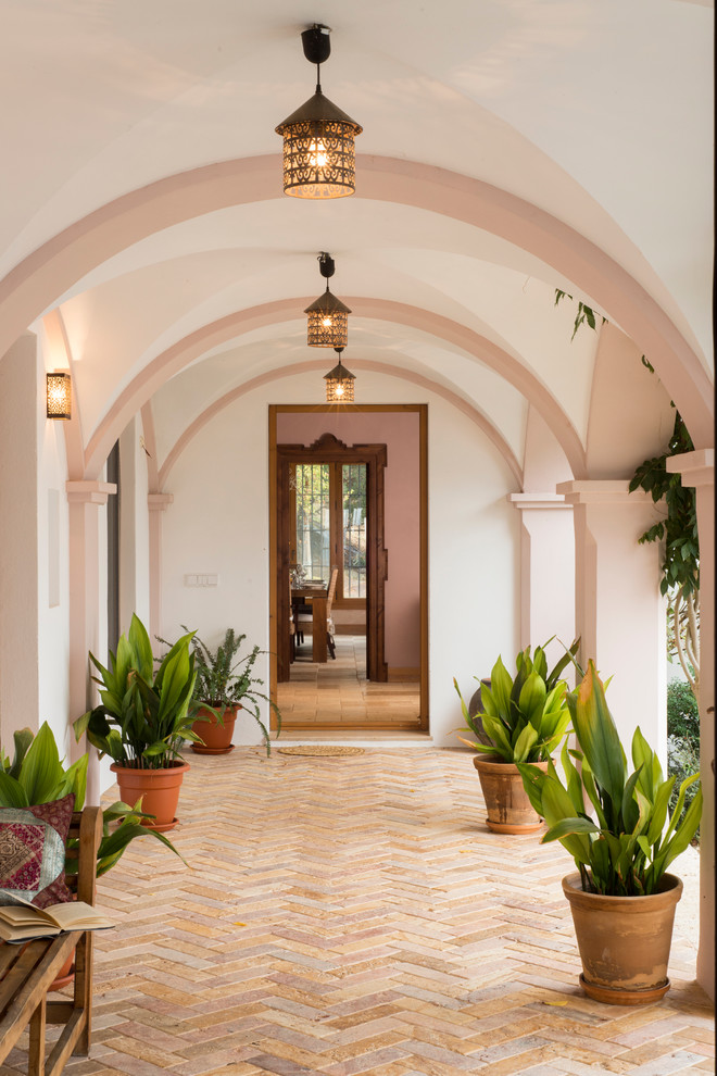 Idée de décoration pour un grand porche d'entrée de maison méditerranéen avec des pavés en brique et une extension de toiture.