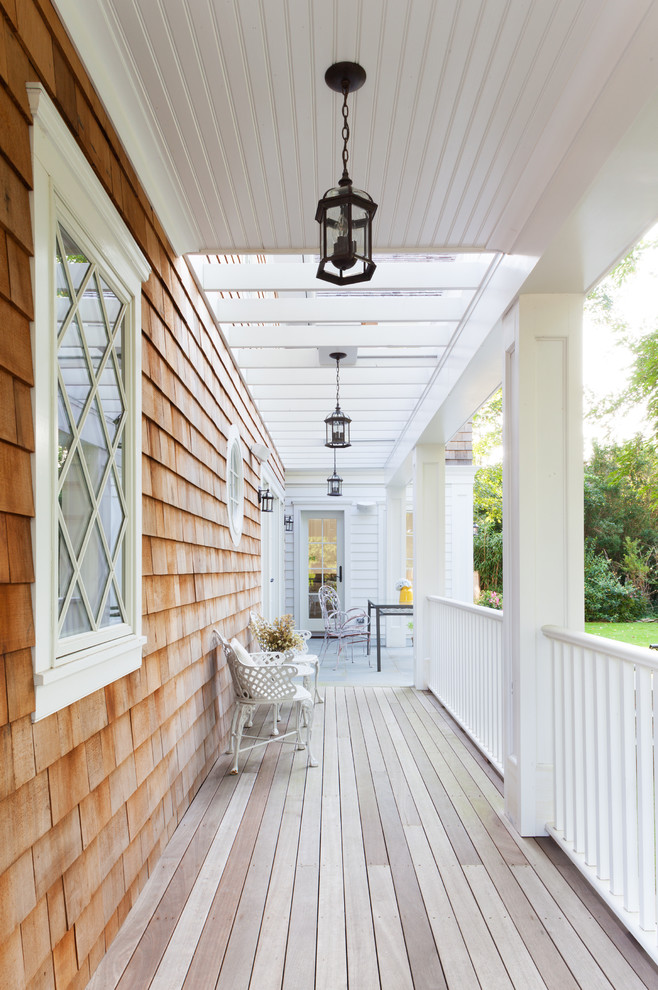 Cette photo montre un porche d'entrée de maison bord de mer avec une terrasse en bois et une extension de toiture.