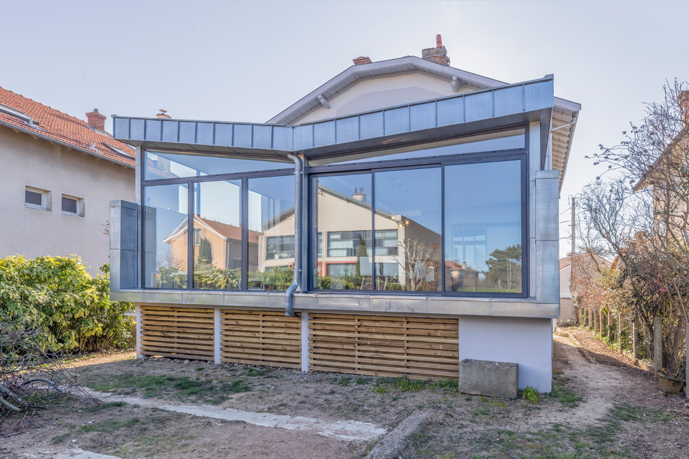 Exemple d'une grande véranda tendance avec parquet clair, un poêle à bois, un manteau de cheminée en carrelage, un plafond standard et un sol beige.