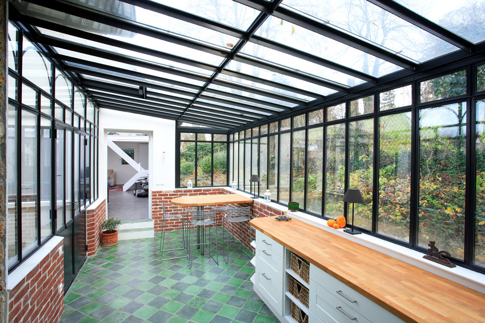 Immagine di una grande veranda industriale con nessun camino, soffitto in vetro e pavimento multicolore