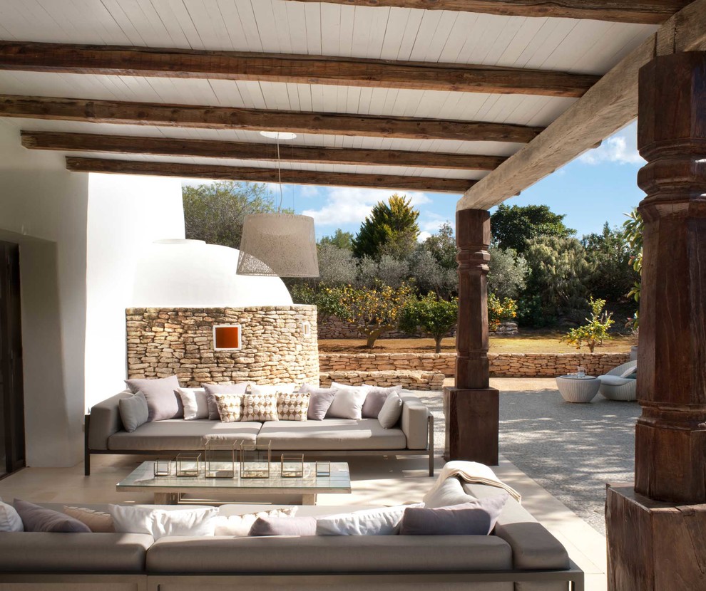 Cette image montre un porche d'entrée de maison arrière méditerranéen de taille moyenne avec une extension de toiture et des pavés en pierre naturelle.