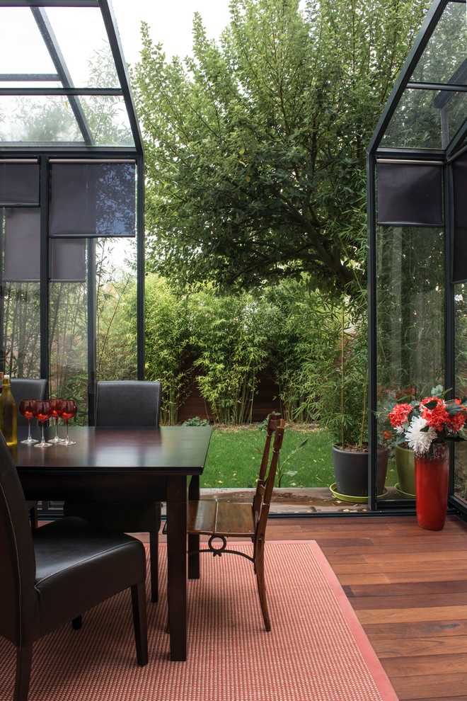 Esempio di una veranda design di medie dimensioni con pavimento in legno massello medio, nessun camino e soffitto in vetro