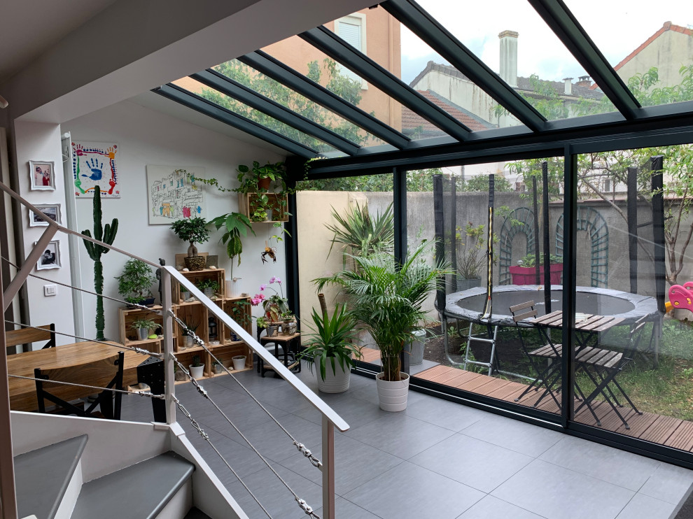 Ispirazione per una veranda design di medie dimensioni con stufa a legna, soffitto in vetro e pavimento grigio