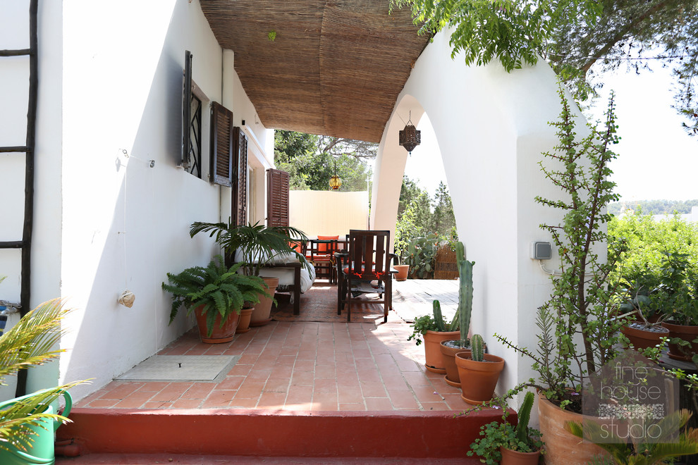 Réalisation d'un grand porche d'entrée de maison avant méditerranéen avec des pavés en pierre naturelle.