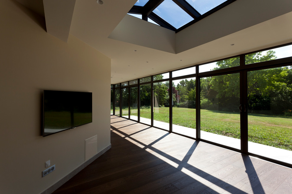 Modelo de galería contemporánea grande con suelo de madera en tonos medios, techo con claraboya y suelo marrón