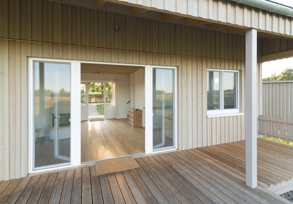Idée de décoration pour un porche d'entrée de maison nordique de taille moyenne avec une moustiquaire, une terrasse en bois et une extension de toiture.