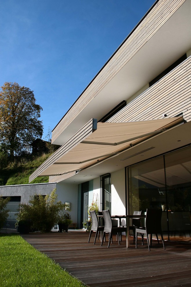 Modelo de terraza contemporánea extra grande en patio trasero con jardín de macetas y toldo