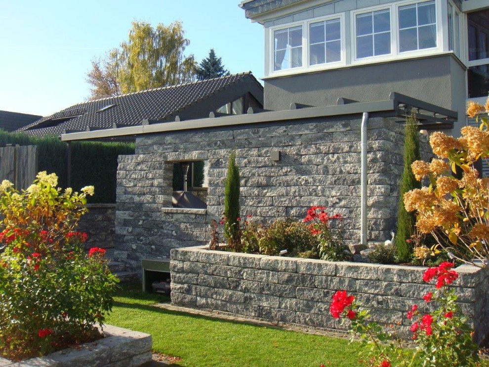Immagine di un portico country di medie dimensioni e dietro casa con pavimentazioni in pietra naturale e un parasole