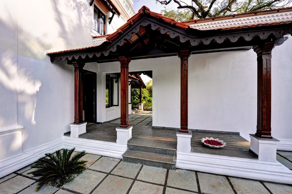 Réalisation d'un grand porche d'entrée de maison latéral asiatique avec des pavés en pierre naturelle et une extension de toiture.