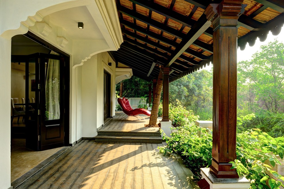 Réalisation d'un grand porche d'entrée de maison arrière asiatique avec une extension de toiture et une terrasse en bois.