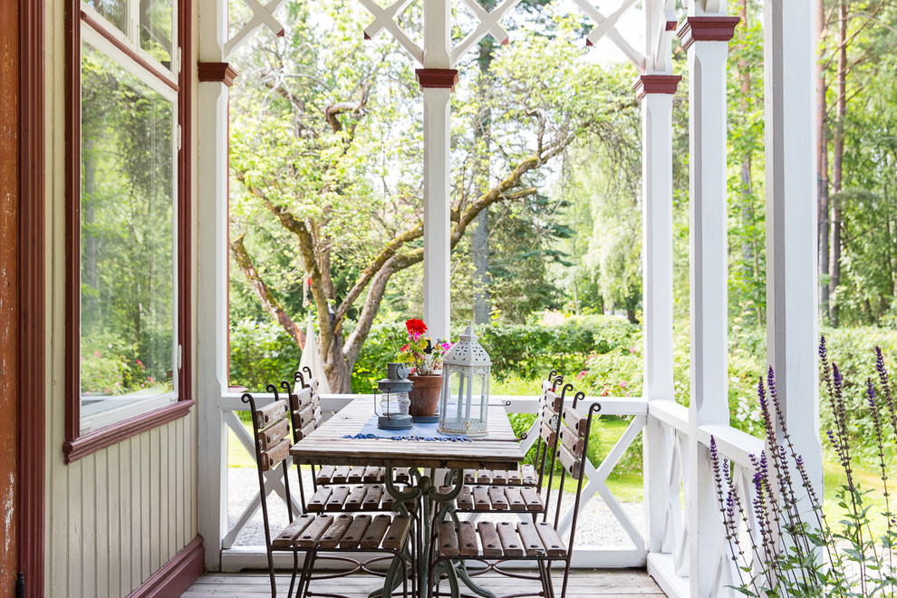 Bild på en lantlig veranda framför huset, med trädäck och en pergola