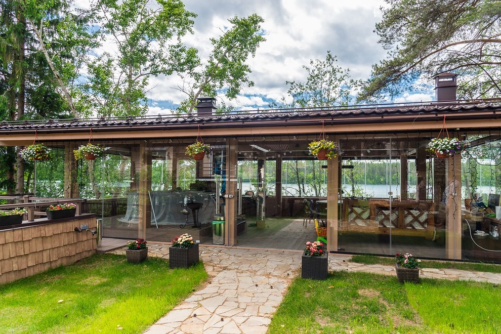 Cette photo montre un grand porche d'entrée de maison avant nature avec une cuisine d'été et des pavés en pierre naturelle.