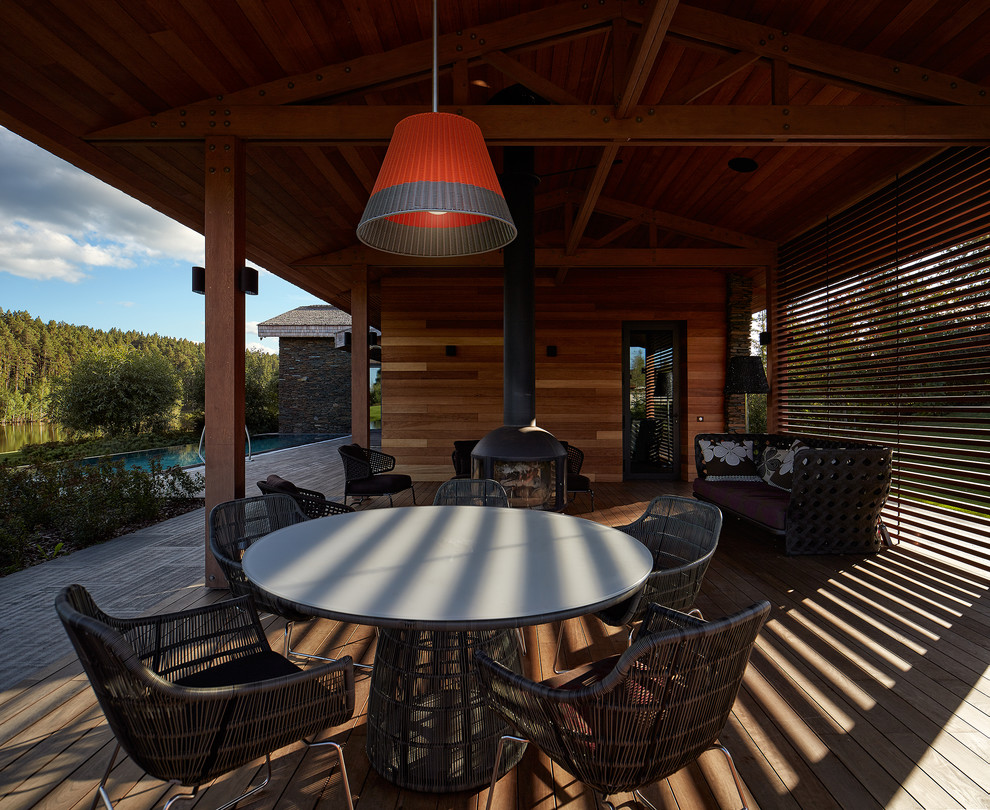 Inspiration pour un porche d'entrée de maison avant design de taille moyenne avec une terrasse en bois, une extension de toiture et un foyer extérieur.